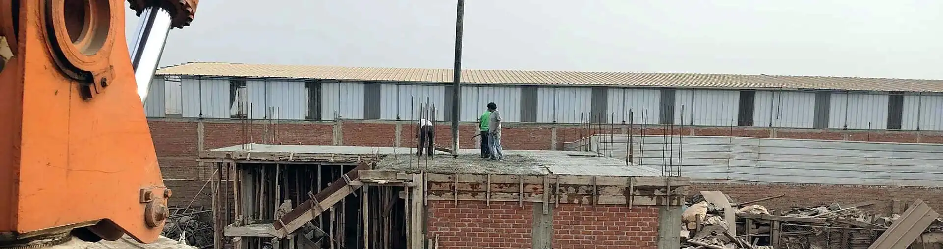 Bomba pluma de concreto junto a un edificio en construcción