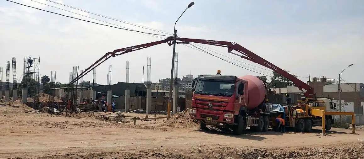 Bomba pluma y mixer de concreto premezclado trabajando en una obra