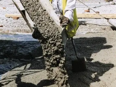 Concreto saliendo por la canaleta de un mixer mientras un obrero lo reparte con lampa