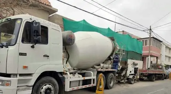 Mixer blanco estacionado junto a una obra cercada con malla verde