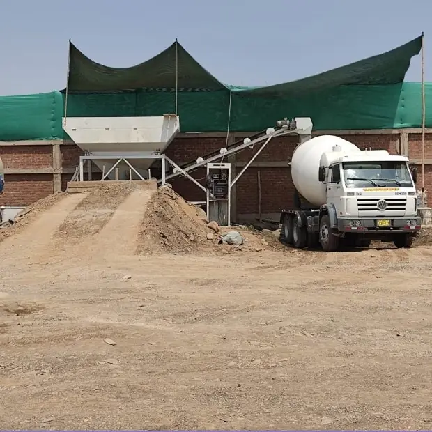 Planta dosificadora de concreto con malla verde y un mixer listo para cargar